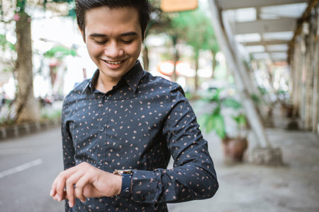 Businessman walking trough sidewalk smiling looking at his wrist watchの写真素材
