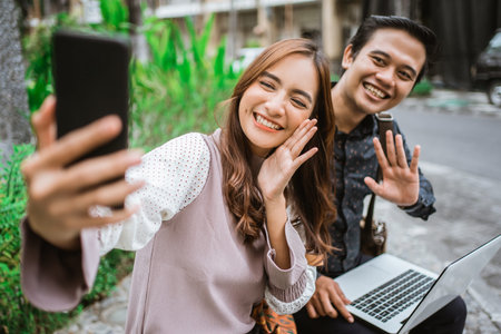 Happy woman using a smart phone taking selfie and video call with her partner