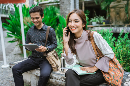 two busy worker sitting in the park during office break using phone
