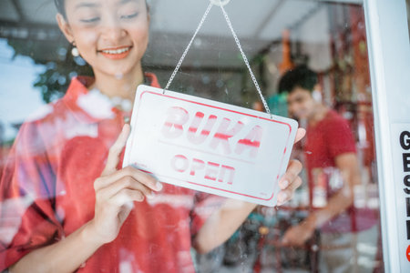 a girl wearing a red t-shirt with an open sign on the front glass door