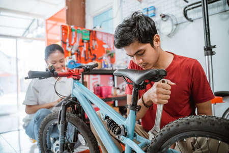 young mechanic assembling a new bicycle using a wrench in the shopの写真素材