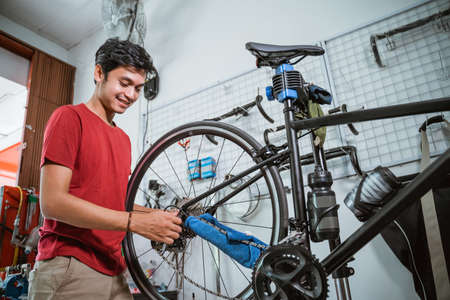 handsome mechanic working tighten the bicycle axle with a wrenchの写真素材