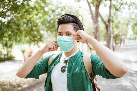 Asian man putting on a medical disposable mask to avoid viruses.の写真素材