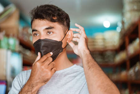 small business owner wearing face mask in front of his shopの写真素材