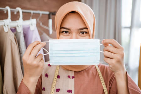 Coronavirus. Asian woman putting on a medical disposable mask to avoid viruses.の写真素材
