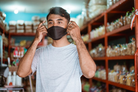 small business owner wearing face mask in front of his shopの写真素材