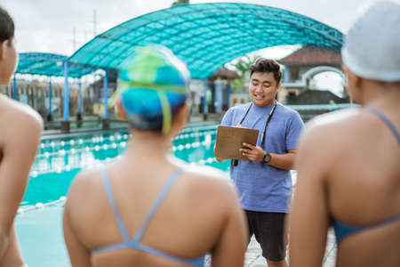 a coach gives instructions to a teenage swimmer in a swimsuitの写真素材