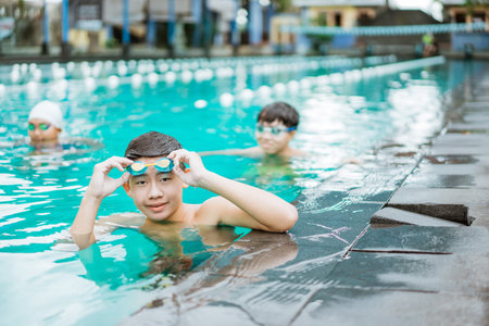 A teenage boy smiles while taking off his swimming goggles