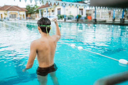 shot from behind of male athlete with clenched fist in pool after entering the finish lineの写真素材