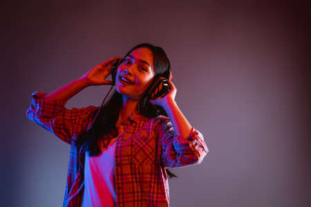 beautiful woman smiling at camera while listening to music wearing headphonesの写真素材