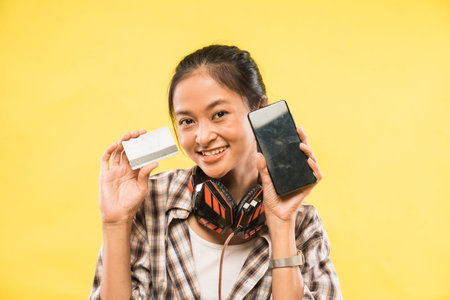 a smiling girl showing a credit card and a smartphone camera