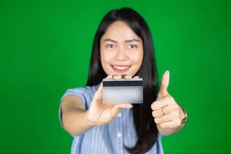 asian woman looking at camera while holding atm card with thumbs upの写真素材