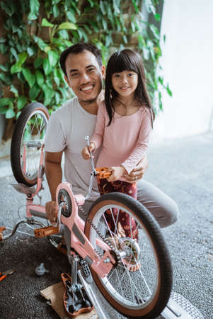 Father and daughter smiling for the camera holding a wrenchの写真素材