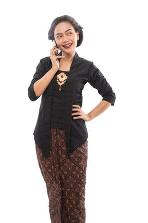 Javanese woman with traditional Kebaya dress thinking gesture holding smartphoneの写真素材