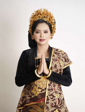 Smiling balinese woman wearing traditional clothes with welcome gestureの写真素材