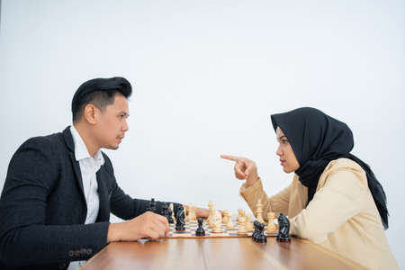Man and woman looking at each other while playing chessの写真素材