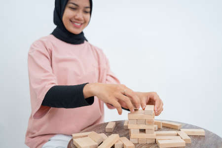 Woman in veil arranging blocks while playing wooden block towerの写真素材
