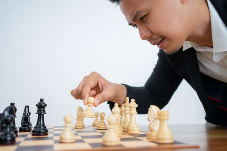 Asian man with hands holding pawn while playing chessの写真素材
