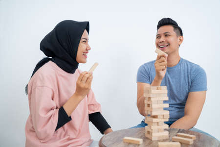 Woman and man holding blocks while playing tower of blocksの写真素材
