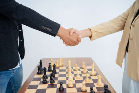 Male and female hands shaking hands over chess piecesの写真素材