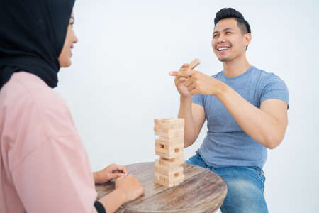 Smiling man holding block with finger pointing at female friendの写真素材
