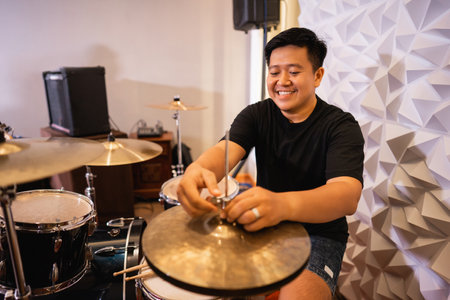 a male drummer prepares hi-hat cymbals before being usedの写真素材