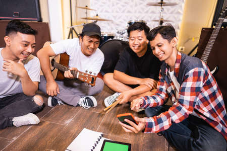 band members chat together sitting on the floor composing songsの写真素材