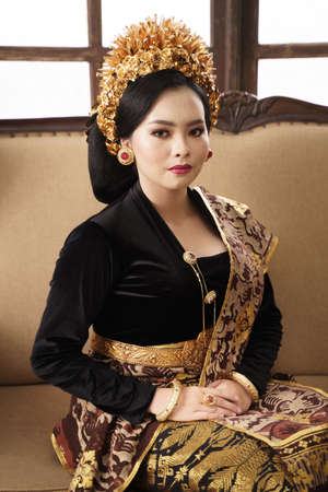 Woman sitting wearing jewellery, Payas crown and Balinese Kebayaの写真素材