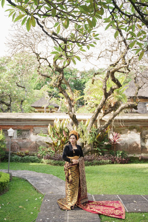 Woman wearing Balinese kebaya and woven cloth standingの写真素材