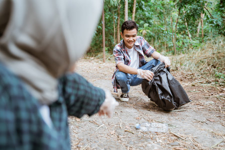 two happy teenage volunteers picking up trashの写真素材
