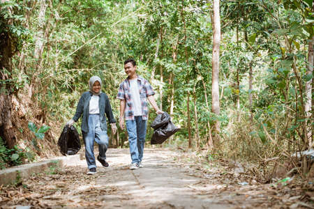 two happy teenage volunteers picking up trashの写真素材