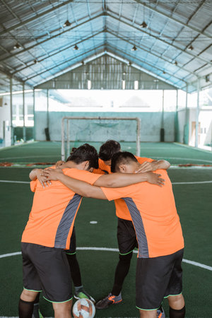 group of male futsal players standing in a circle prayingの写真素材