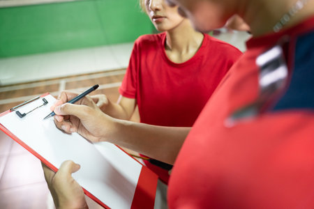 Coach gives instructions to players using pen and clipboardの写真素材
