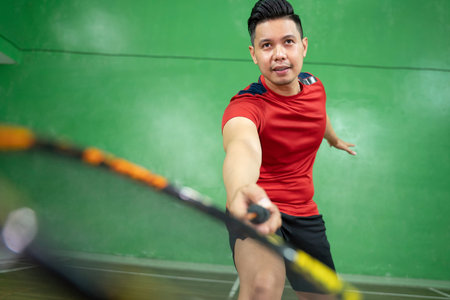 Close up of a male badminton player swinging a racket