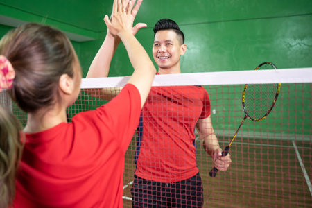 Male and female badminton players doing high fiveの写真素材