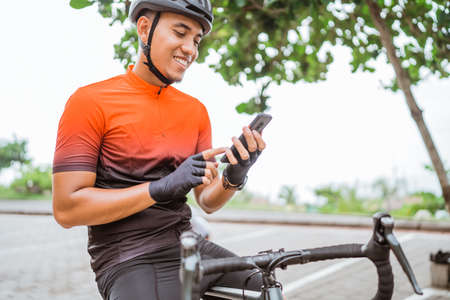 road bike cyclist sitting on his bike while using mobile phoneの写真素材