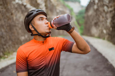 road bike cyclist take a brake and drink a bottle of waterの写真素材