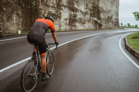 male cyclist riding his bike in country side shoot from the backの写真素材