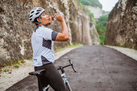 road bike cyclist take a brake and drink a bottle of waterの写真素材