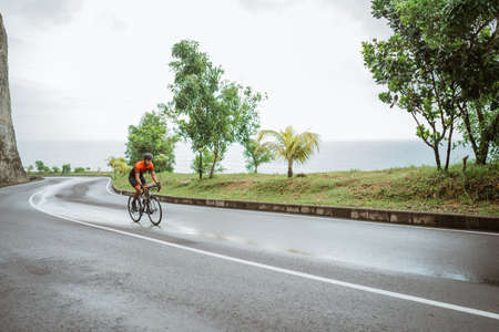 asian male cyclist riding in beautiful roadの写真素材