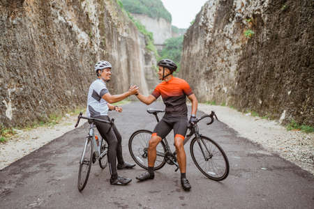 two cyclist friend high five when finish his race togetherの写真素材