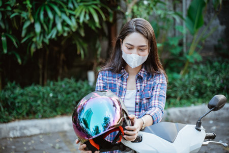 Woman with mask takes helmet before road riding motorbikeの写真素材