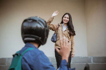Smiling woman happily waving to people riding motorbikesの写真素材