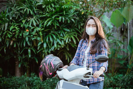 Attractive girl standing wearing mask beside motorcycle with copyspaceの写真素材