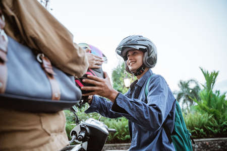 Man gives a helmet to someone while picking himの写真素材