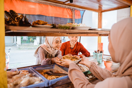 muslim couple sitting on traditional food stall, waiting for iftar timeの写真素材