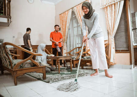 veiled mother mopping the floor while cleaning the house togetherの写真素材
