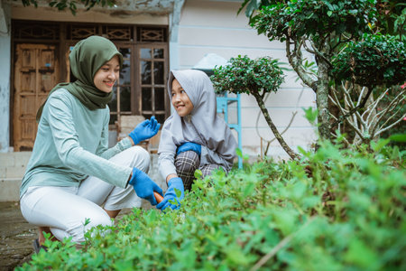 Mother and daughter in headscarves gardening together in the yardの写真素材