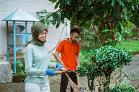 Veiled mother uses plant shears to trim the leavesの写真素材