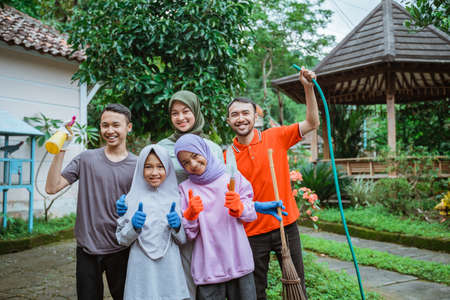 Father, mother and children smiling wearing gloves while gardeningの写真素材